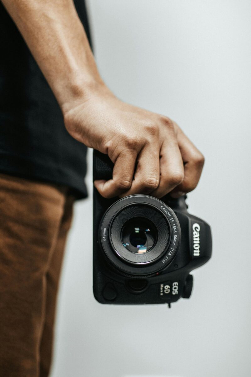 A close-up shot of a hand holding a DSLR camera, ideal for photography concepts.